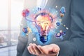 Businessman hand holding hologram of colorful light bulb as a concept of new idea for start up. Concept of creativity and Royalty Free Stock Photo
