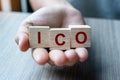 Businessman hand holding ICO Initial Coin Offering word with wooden cube block, is the cryptocurrency industry equivalent to an