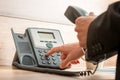 Businessman hand holding a landline telephone receiver dialing a Royalty Free Stock Photo