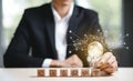 Businessman Hand holding light bulb with Business icon on wood cube and working on desk, Creativity, and innovation are keys to sH Royalty Free Stock Photo