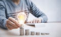 Businessman hand holding light bulb on coins stack on the wooden table , Saving ideas and investment budget, Creative ideas concep Royalty Free Stock Photo