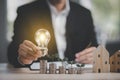 Businessman hand holding light bulb on coins stack on the wooden table , Saving ideas and investment budget, Creative ideas concep Royalty Free Stock Photo