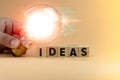 Businessman hand holding a light bulb and wood block with word Ideas. Innovation and creative concept Royalty Free Stock Photo