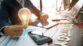 Businessman hand holding lightbulb with business documents and strategy word on office table and banking data on smart phone