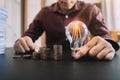 Businessman hand holding lightbulb with and money stack in office, idea saving energy and accounting finance concept Royalty Free Stock Photo