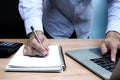 Businessman hand holding a pen to paperwork with laptop on table Royalty Free Stock Photo