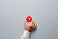 Businessman hand holding a red badge with question mark symbol. Problem, uncertainty or solution in business Royalty Free Stock Photo