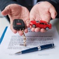 Businessman hand holding red car toy with vehicle keyless, pen and contract document. buy and sale, insurance, rental and contract Royalty Free Stock Photo