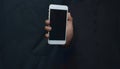 Businessman hand holding a smartphone on a black background Selective focus smartphone media technology concept Royalty Free Stock Photo