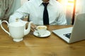 Businessman hand holding tea cup with lemon with laptop on wooden desk in the office Royalty Free Stock Photo