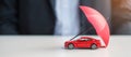 Businessman hand holding umbrella and cover  red car toy on table. Car insurance, warranty, repair, Financial, banking and money Royalty Free Stock Photo
