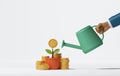 Businessman hand holding watering can to water plant in growing pot with pile of coins on white background