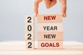 Businessman hand holding wooden block with text 2022 NEW YEAR NEW GOALS on table background. Resolution, strategy, solution, Royalty Free Stock Photo