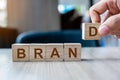 Businessman hand holding wooden cube block with BRAND business word on table background. Marketing, Advertising and Product Royalty Free Stock Photo