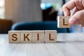 Businessman hand holding wooden cube block with SKILL business word on table background. Ability, Learn, Knowledge, Technical,