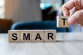 Businessman hand holding wooden cube block with SMART business word on table background. Specific, Achievable, Measurable,