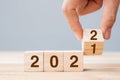 Businessman hand holding wooden cube with flip over block 2021 to 2022 text on table background. Resolution, strategy, solution, Royalty Free Stock Photo