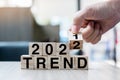Businessman hand holding wooden cube with flip over block 2021 to 2022 TREND word on table background. Resolution, strategy, Royalty Free Stock Photo