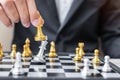 Businessman hand moving gold Chess King figure and Checkmate enermy or opponent during chessboard competition. Strategy, Success,