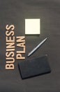 Businessman hand placing a pen and notebook in front of Word Business Plan made of wooden blocks of Alphabet letters. High Angle Royalty Free Stock Photo