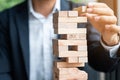 Businessman hand placing or pulling wooden block on the tower. Business planning, Risk Management Royalty Free Stock Photo