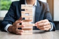 Businessman hand placing or pulling wooden block on the tower. Business planning, Risk Management Royalty Free Stock Photo