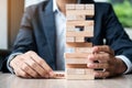 Businessman hand placing or pulling wooden block on the tower. Business planning, Risk Management, Solution and strategy Concepts Royalty Free Stock Photo