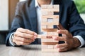 Businessman hand placing or pulling wooden block on the tower. Business planning, Risk Management, Solution and strategy Concepts