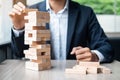 Businessman hand placing or pulling wooden block on the tower Royalty Free Stock Photo