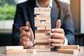 Businessman hand placing or pulling wooden block on the tower Royalty Free Stock Photo