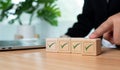 Businessman hand pushes the correct green symbol on a wooden cube for a business proposal and concept approval document