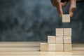 Businessman hand putting blank wooden cube block stack on dark background with copy space Royalty Free Stock Photo