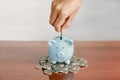 Businessman hand putting coin into blue piggy bank Royalty Free Stock Photo