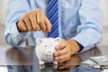 Businessman hand putting coin into blue piggy bank, saving money for future investment plan and retirement fund concept Royalty Free Stock Photo