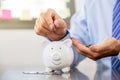 Businessman hand putting coin into blue piggy bank, saving money for future investment plan and retirement fund concept Royalty Free Stock Photo