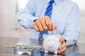 Businessman hand putting coin into blue piggy bank, saving money for future investment plan and retirement fund concept Royalty Free Stock Photo