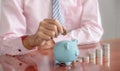 Businessman hand putting coin into blue piggy bank Royalty Free Stock Photo