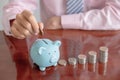 Businessman hand putting coin into blue piggy bank Royalty Free Stock Photo