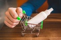 Businessman hand rolls small shopping cart with antiseptic, close-up