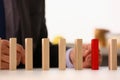 Businessman hand selects red wooden block on table