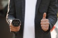 Businessman hand showing thumbs up holding power type 2 cable supply plugged at electric car charging station. Man Royalty Free Stock Photo