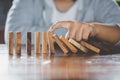 Businessman hand stopping falling wooden dominoes effect from c