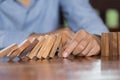 Businessman hand stopping falling wooden dominoes effect from continuous toppled or risk, strategy and successful intervention Royalty Free Stock Photo