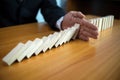 Businessman hand stops domino continuous overturned meaning that hindered business failure. Stop over this business failure