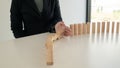 Businessman hand strongly is stoping dominoes continuous toppled.