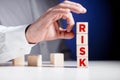 Businessman hand is about to flick the wooden cubes with the word risk. To avoid or eliminate risk Royalty Free Stock Photo