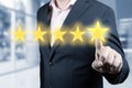 Businessman hand touching five star symbol. Man Is Pointing Five Stars - Review And Rating Concept. blurred office background Royalty Free Stock Photo