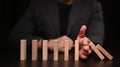 Businessman hand trying to stop dominoes. Protection finance from domino effect concept. Royalty Free Stock Photo