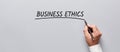 Businessman hand underlining the word business ethics on gray background. The ethics of business