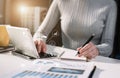 Businessman hand working at a computer and writing on a notepad with a pen in the office. Royalty Free Stock Photo